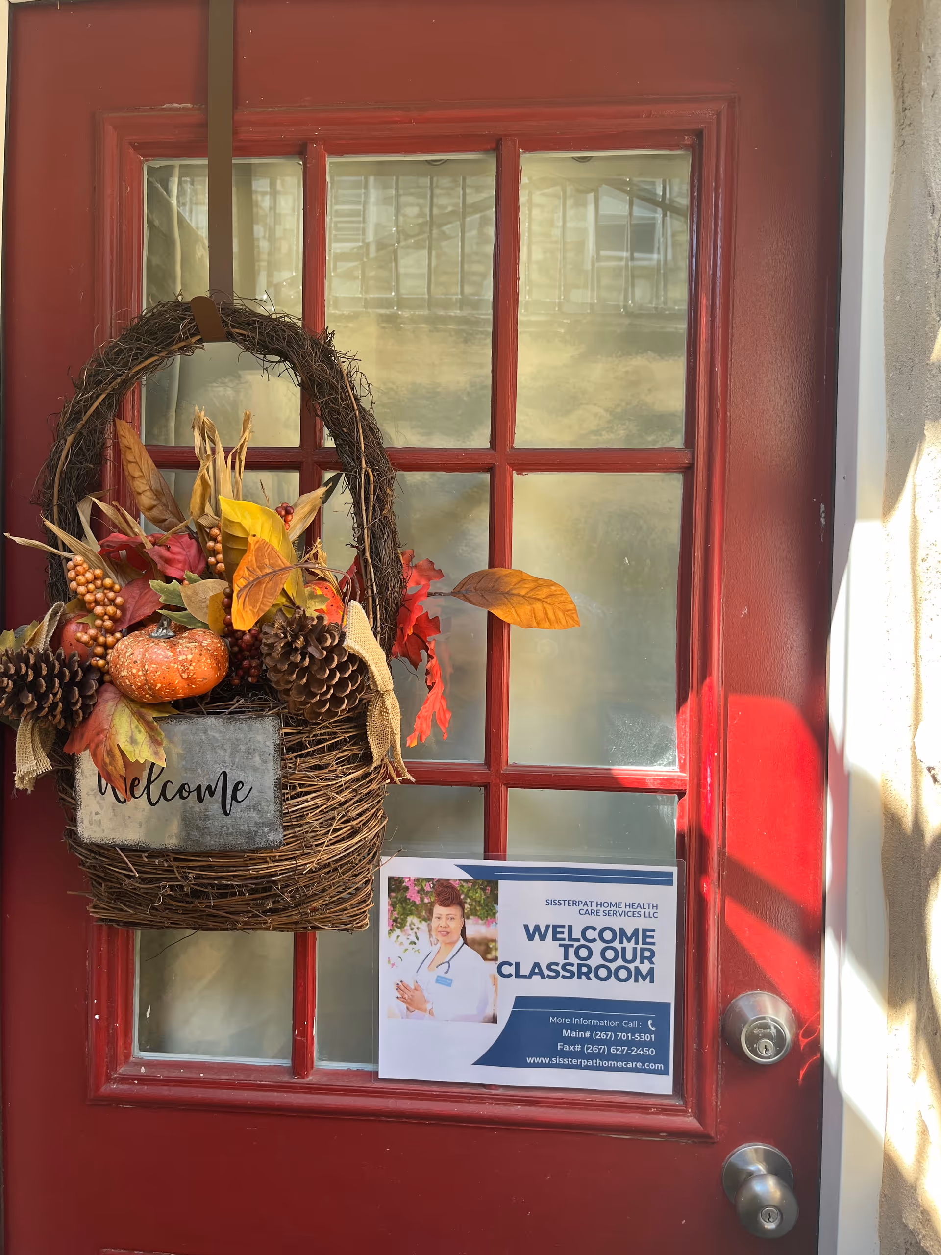 Red front door with fall wreath and welcome sign outside a care facility.