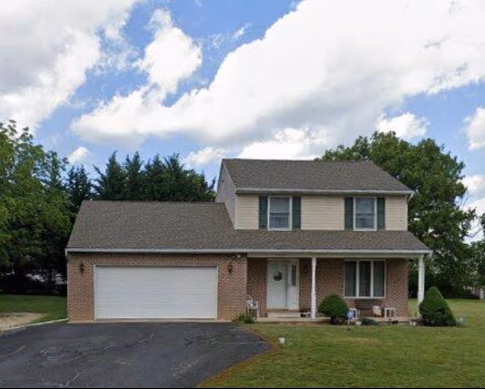 Two-story house with brick lower level, beige siding, and a two-car garage
