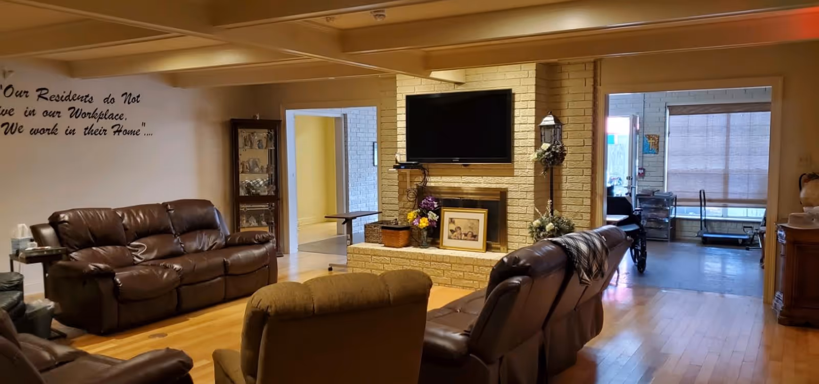 Cozy common lounge at Dr. Violet T. Lewis Village with leather seating, brick fireplace, and TV.