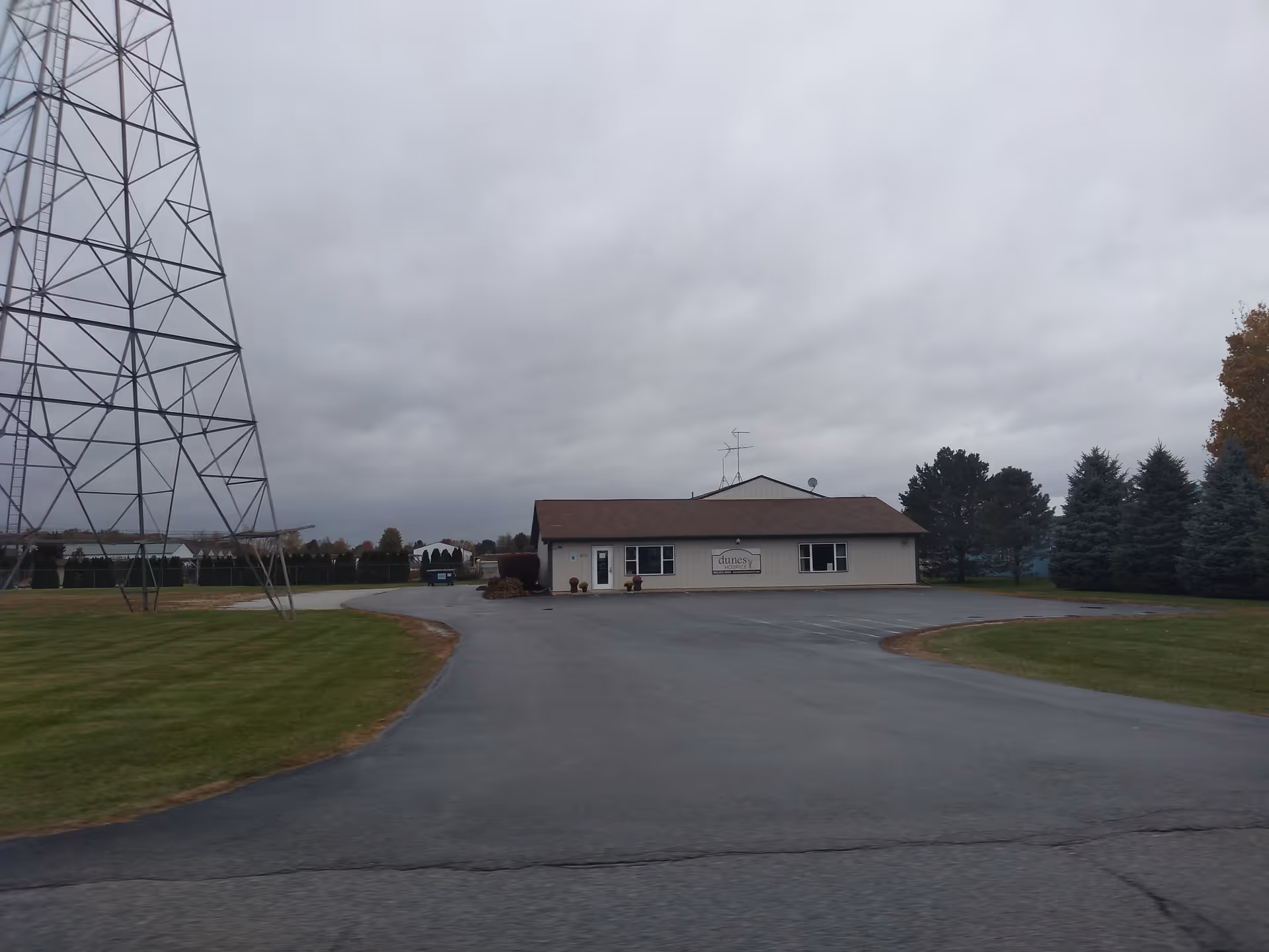 Front view of a single-story hospice building against cloudy sky and trees.
