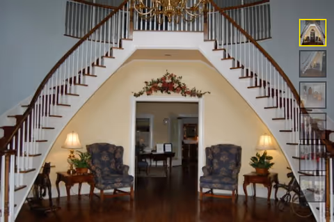 Elegant two-arched staircase dominates a bright foyer with seating and lamps.