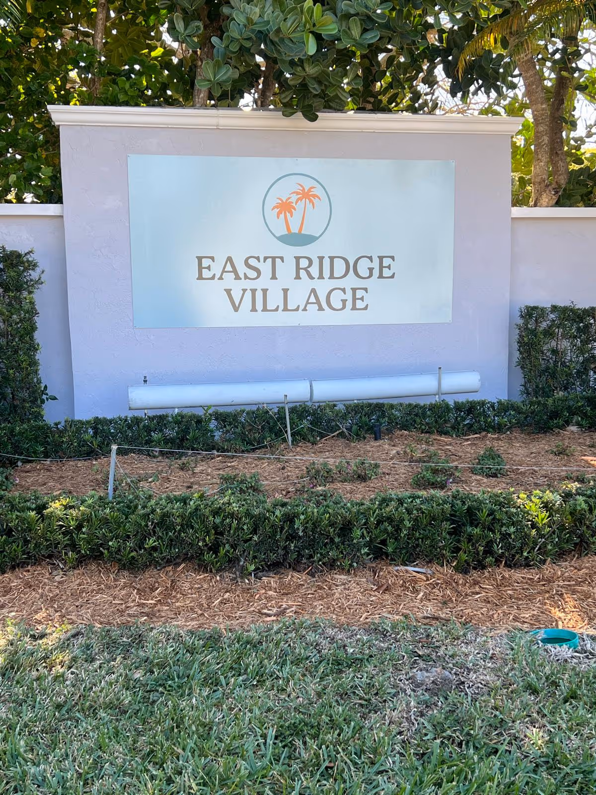 Front exterior sign reading East Ridge Village, with shrubs and mulch.