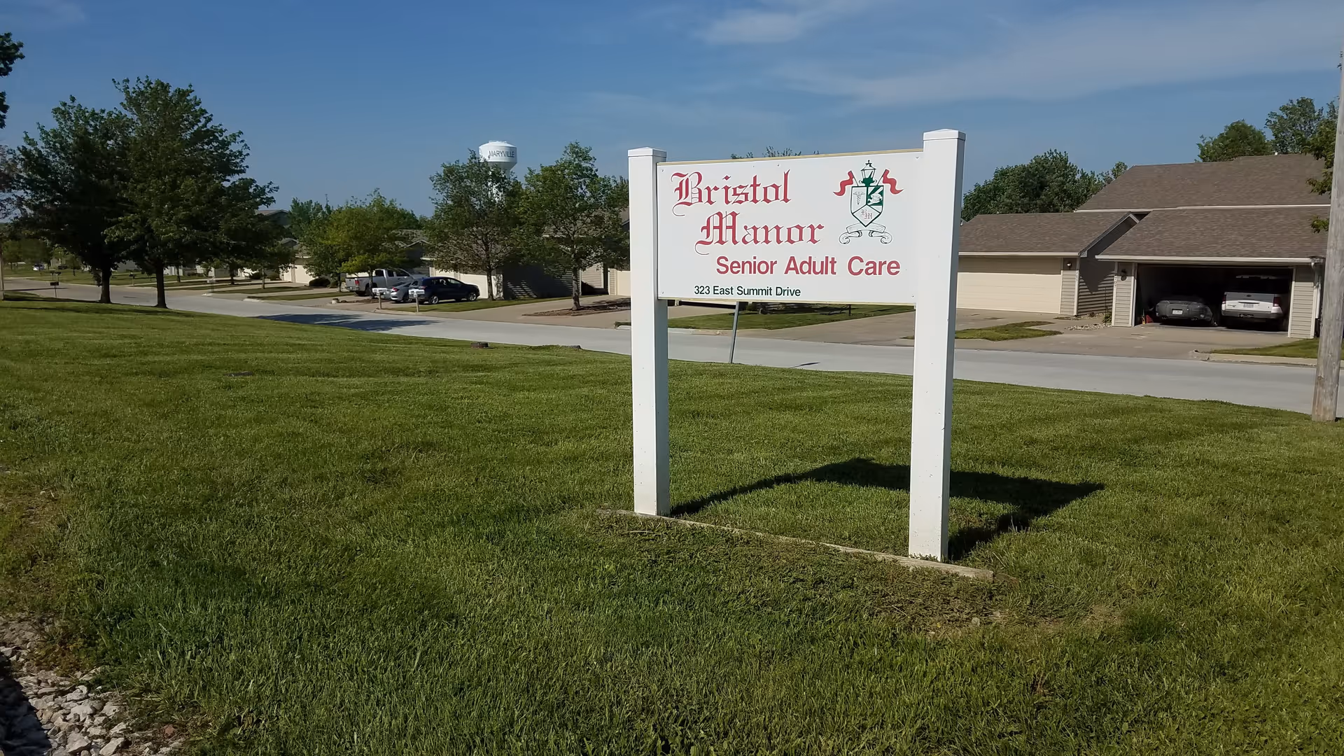Exterior view of Bristol Manor sign on a grassy lawn with a building behind