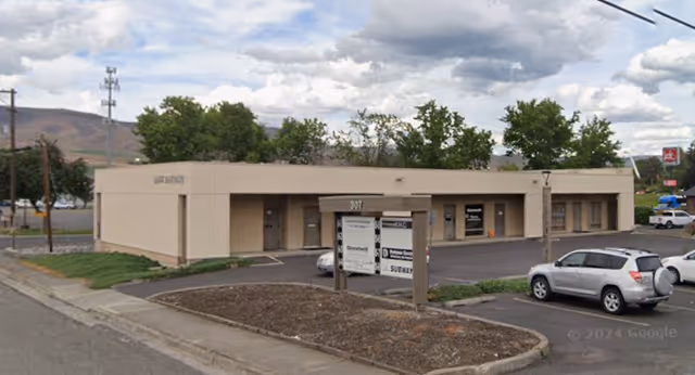 Exterior view of Idaho In Home Care facility with a parking lot and hills behind.