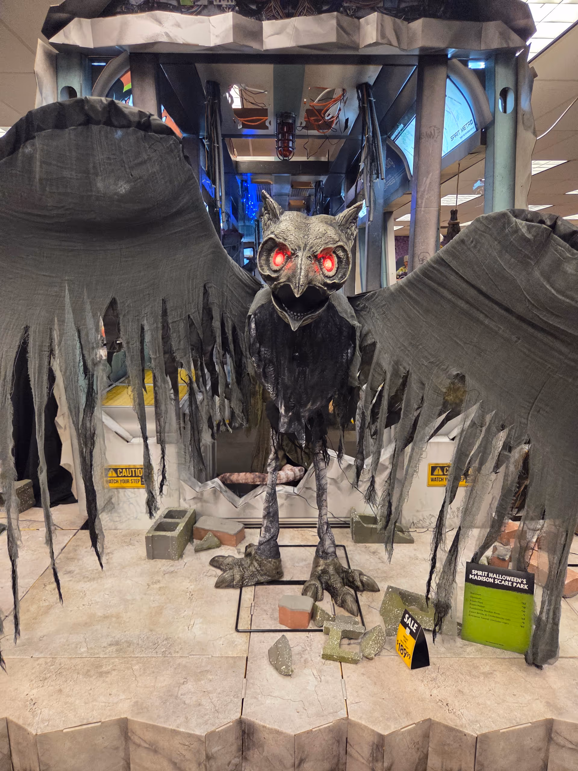 Life-size winged Halloween creature prop with red eyes in store display.