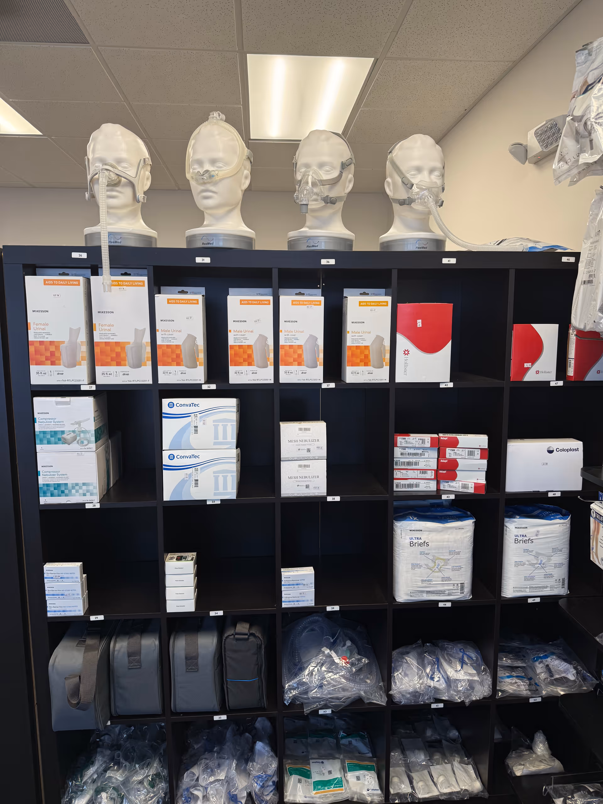 Shelving unit stocked with medical supplies and mannequin heads in a storage room.