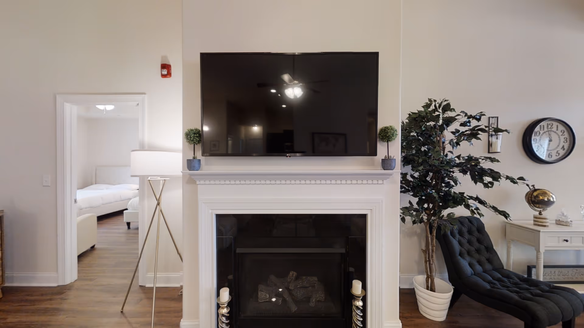 Living room with fireplace, mounted TV, plants, and a tufted chair.