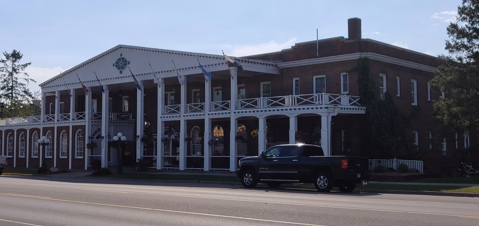 Exterior view of a senior living facility with a covered porch and flags.