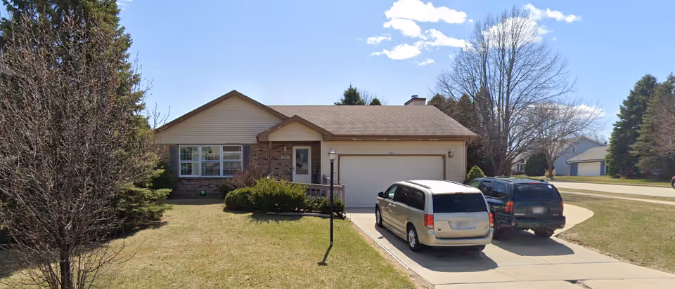 Two-car driveway with a van and a dark SUV parked in front of a single-story home.