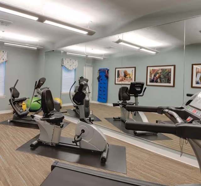 Victory Crossing Senior Apartments gym with treadmills, stationary bikes, and mirrored fitness room.
