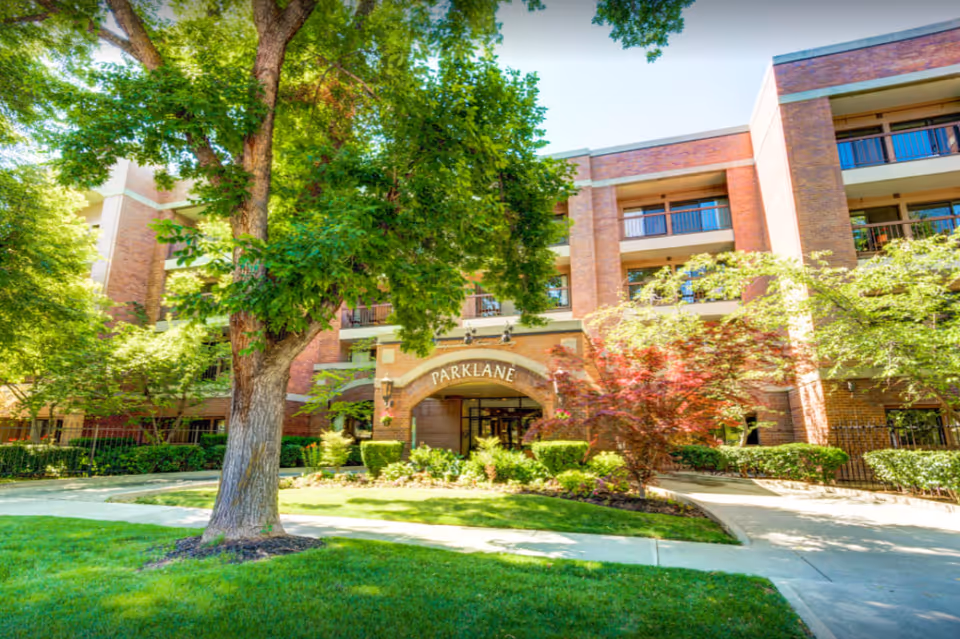 Park Lane Senior Living building with brick exterior, trees, and landscaped entrance