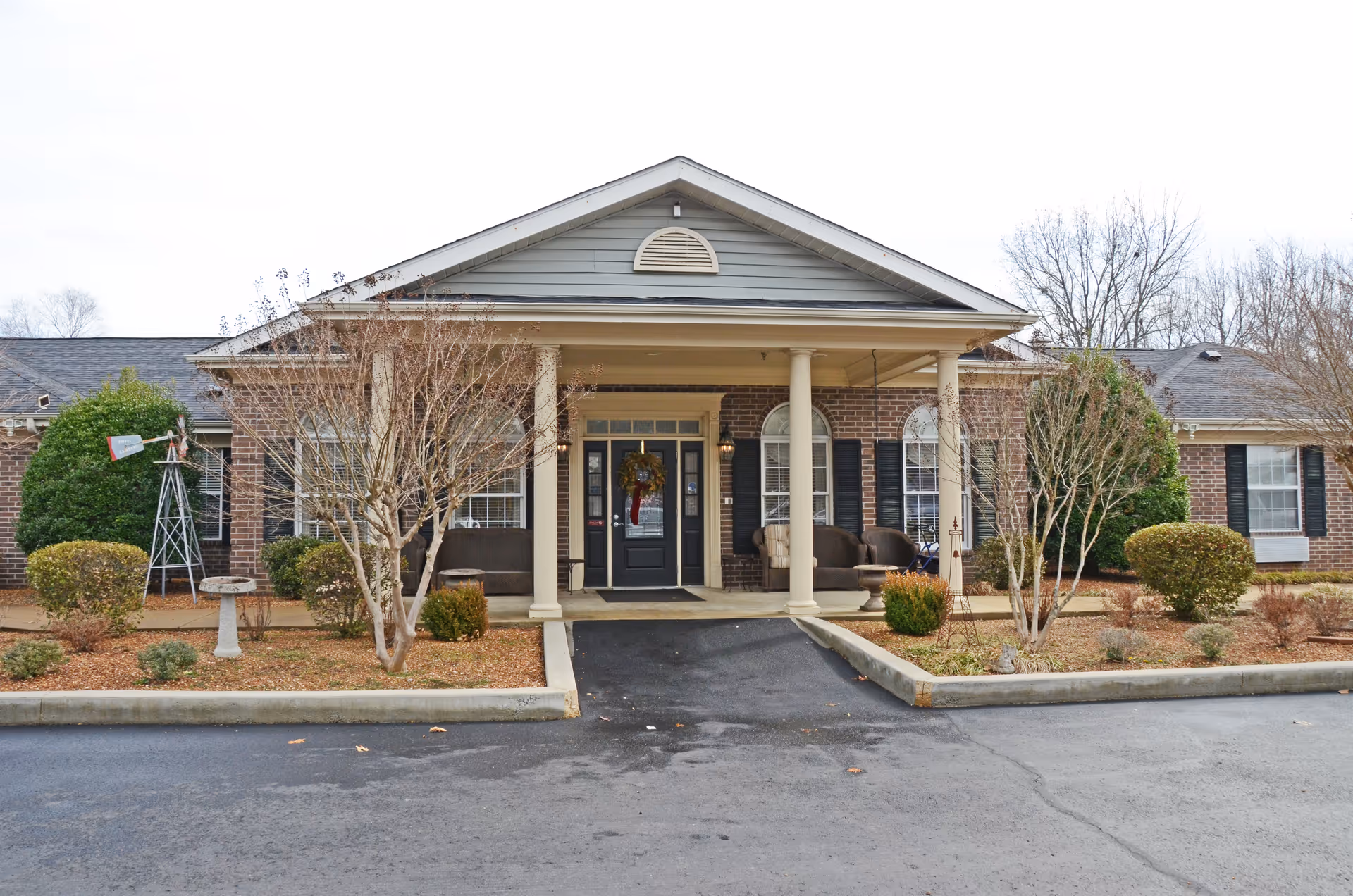 Front view of Eiffel Gardens senior living facility with brick exterior and porch seating.