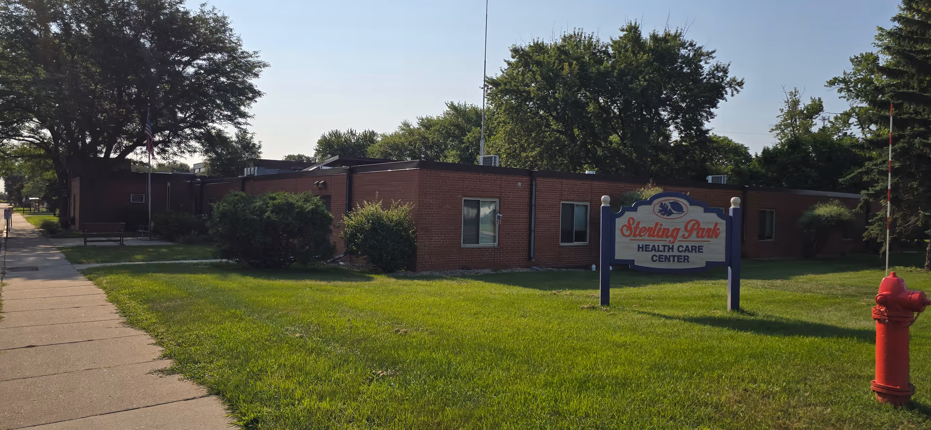Exterior view of Sterling Park Health Care Center building with green lawn and sidewalk.