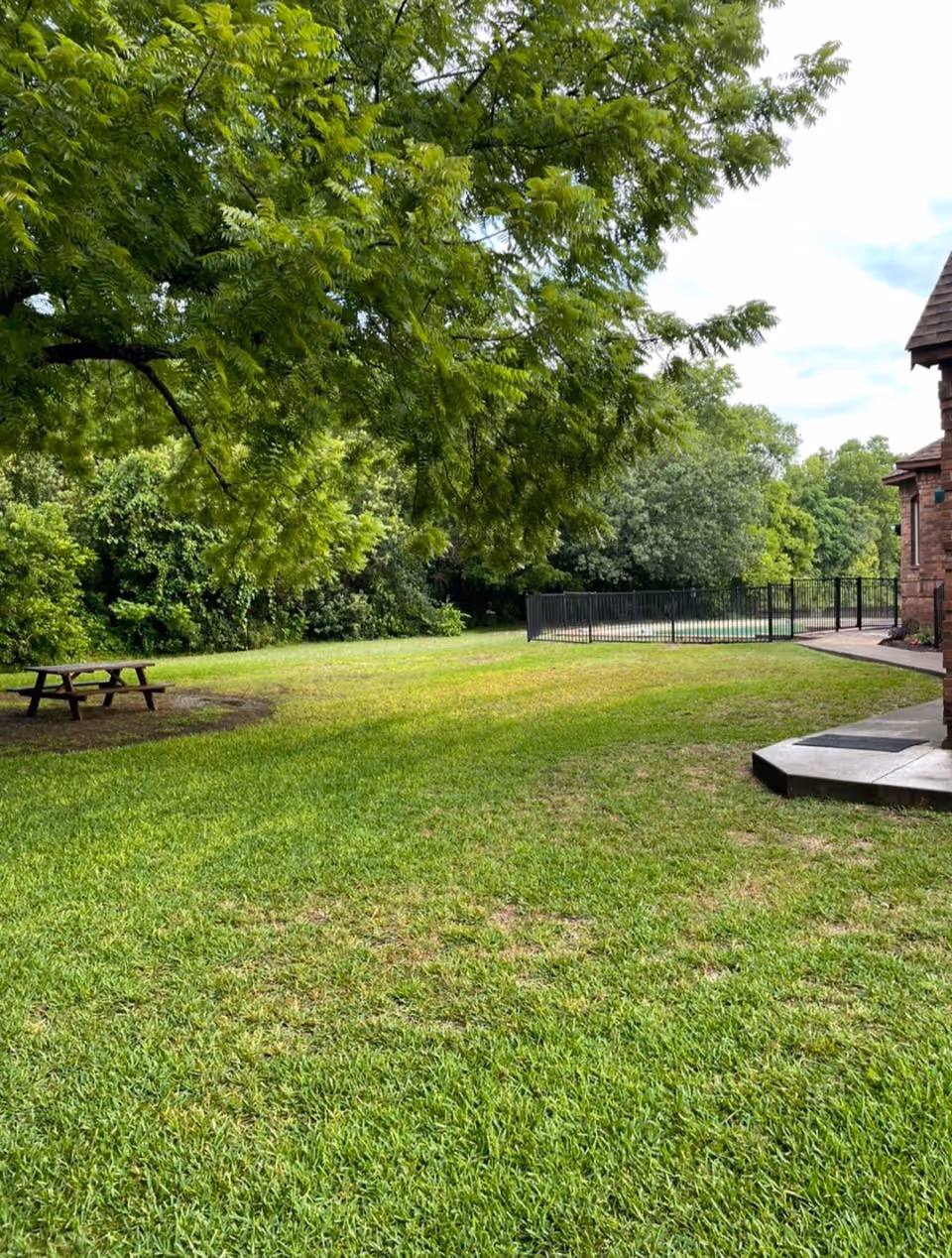 A spacious green lawn area with a picnic table and trees at Brookside Farm senior living facility.