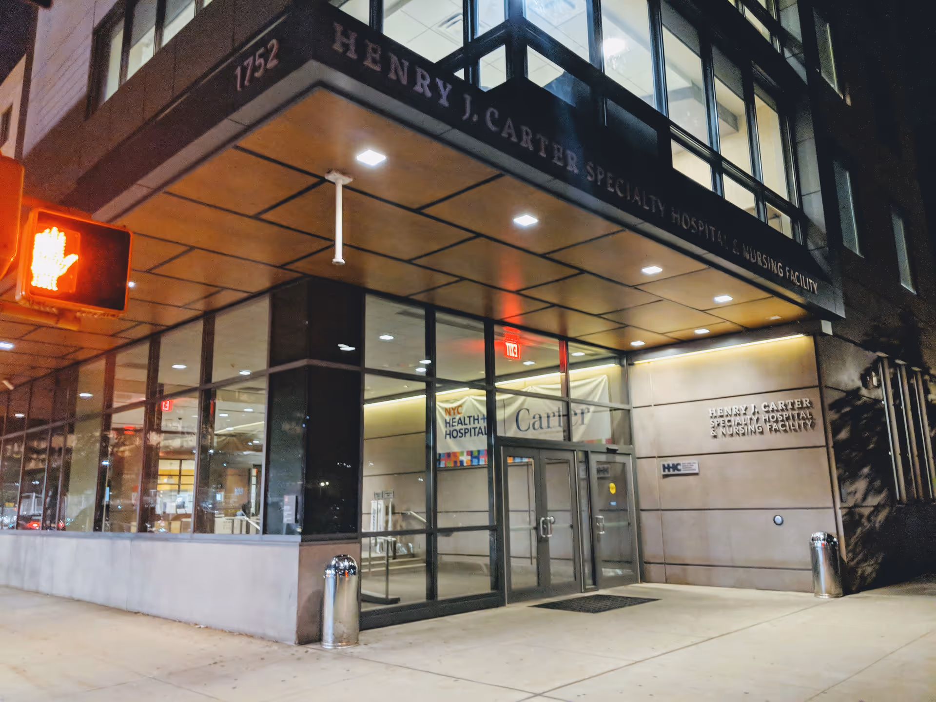 Night exterior view of Henry J. Carter Specialty Hospital & Nursing Facility entrance with glass doors.