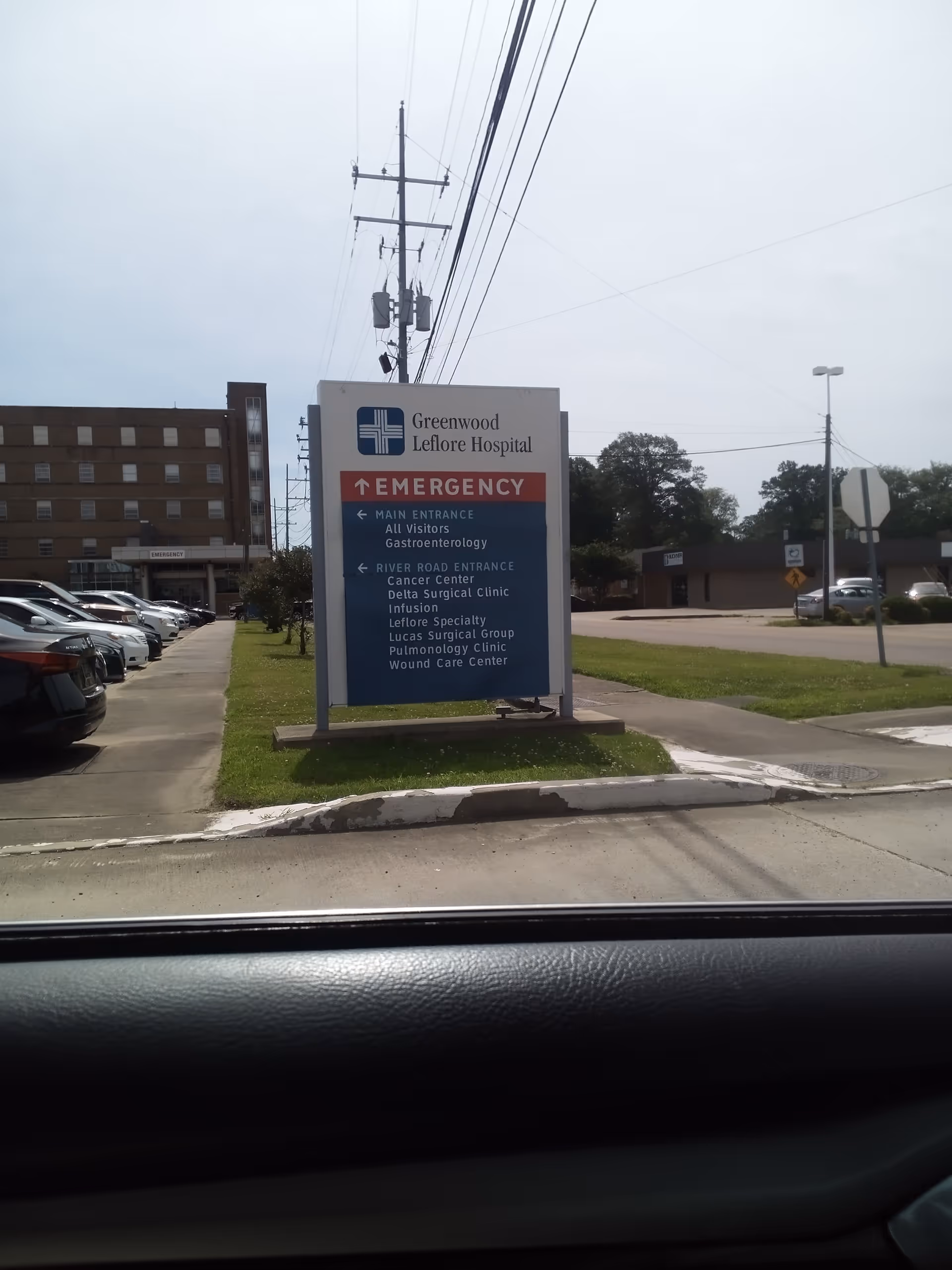 Outdoor sign for Greenwood Leflore Hospital with emergency entrance and parking area.