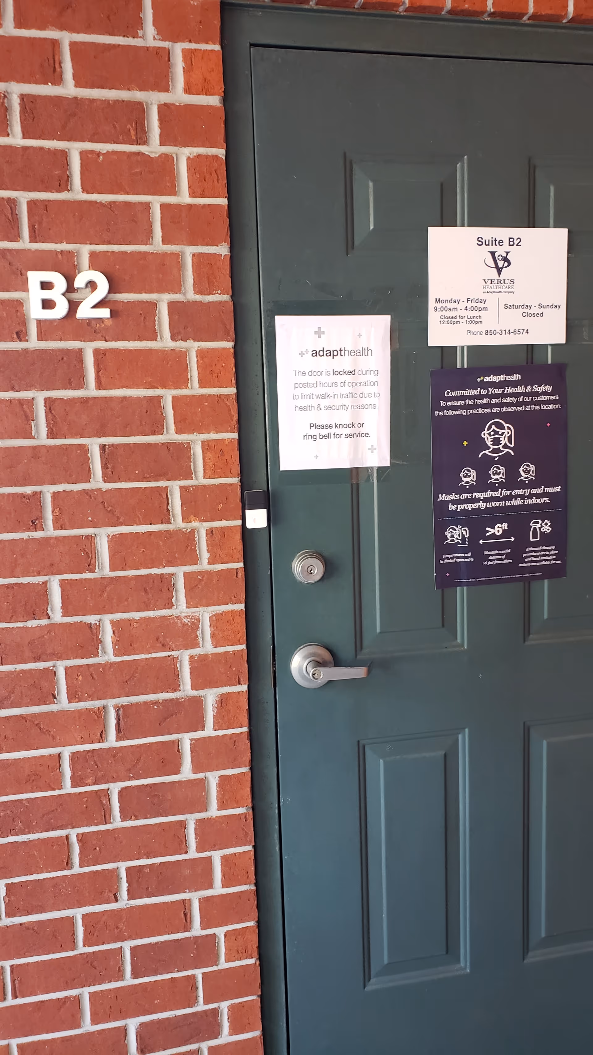 Door on brick wall labeled B2 with posted notices and signs.