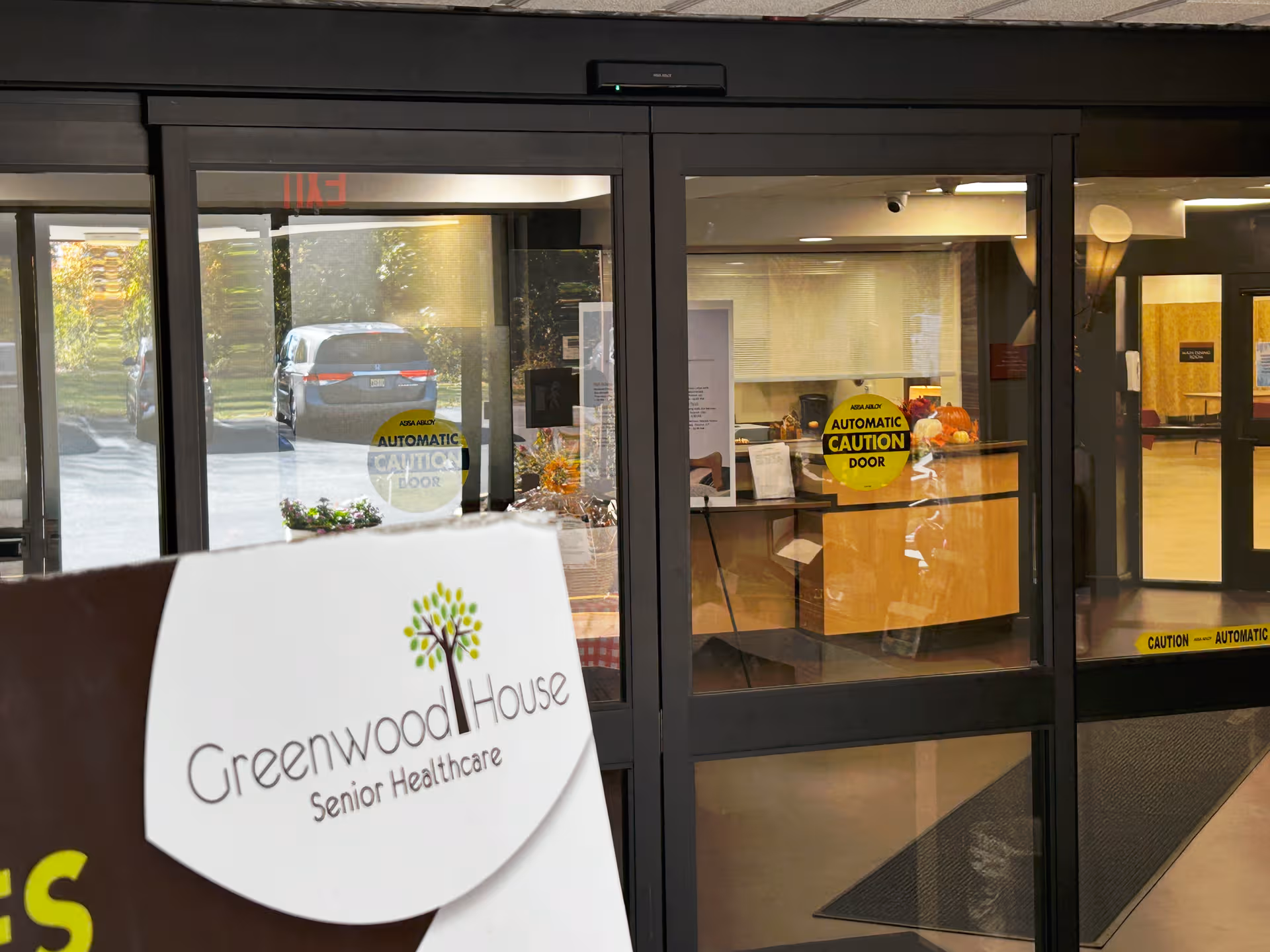 Front entrance of Greenwood House Senior Healthcare with glass doors and a reception area.