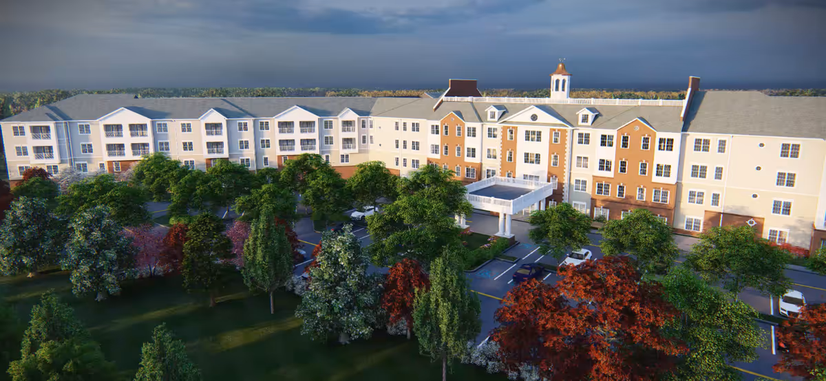 A large multi-story senior living facility with a central entrance and surrounding trees.