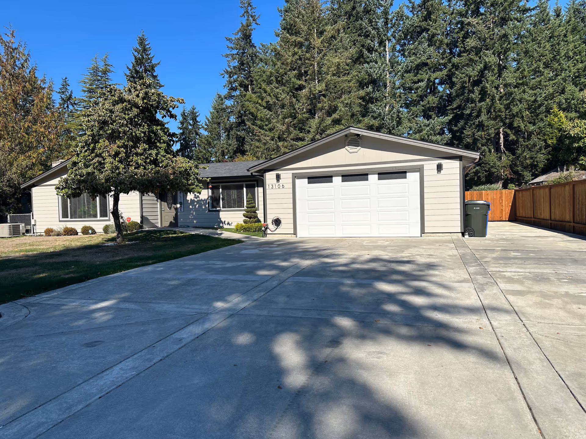 Front exterior of a single-story home with driveway, trees, and a two-car garage.