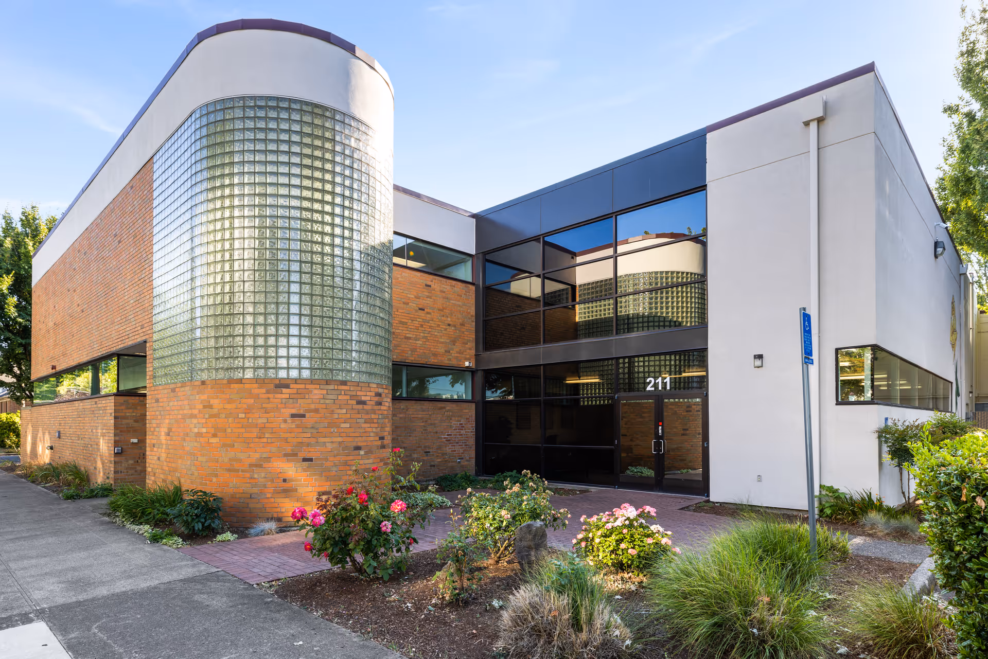Exterior view of a modern brick-and-glass building with landscaped entrance.