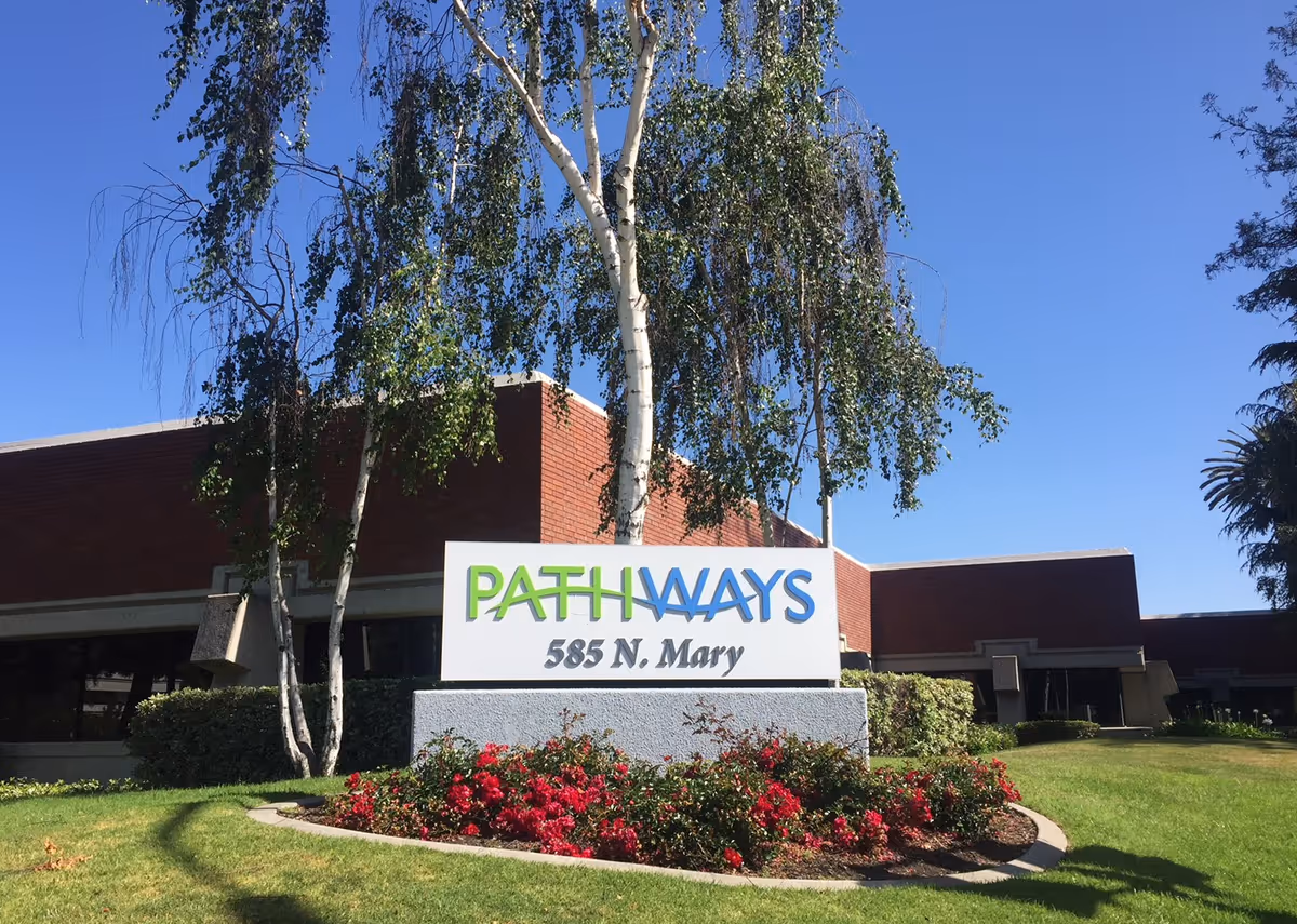 Pathways sign in front of brick building with landscaped lawn and trees