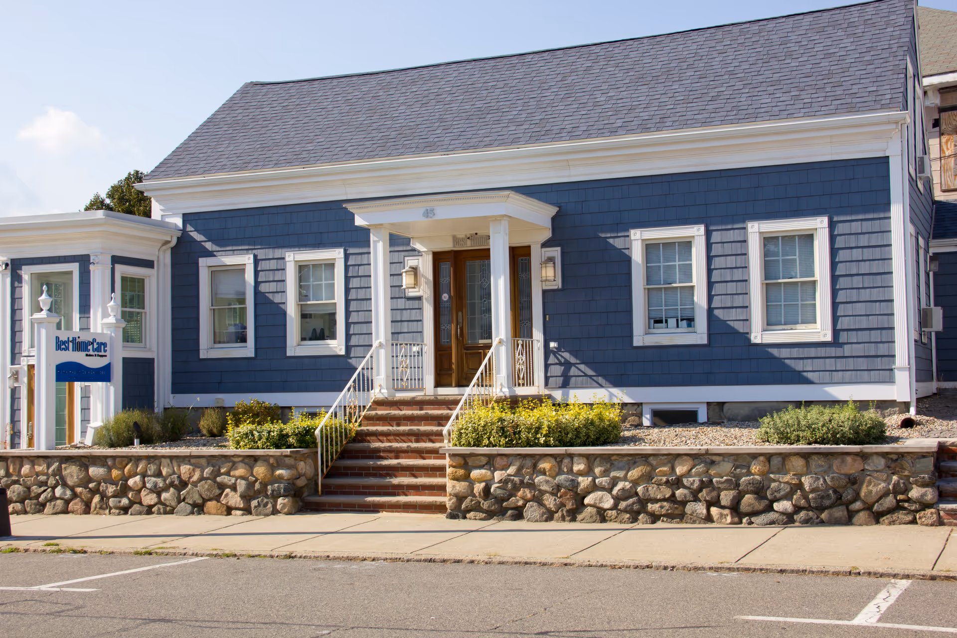 Blue senior living facility exterior with front steps and Best Home Care sign