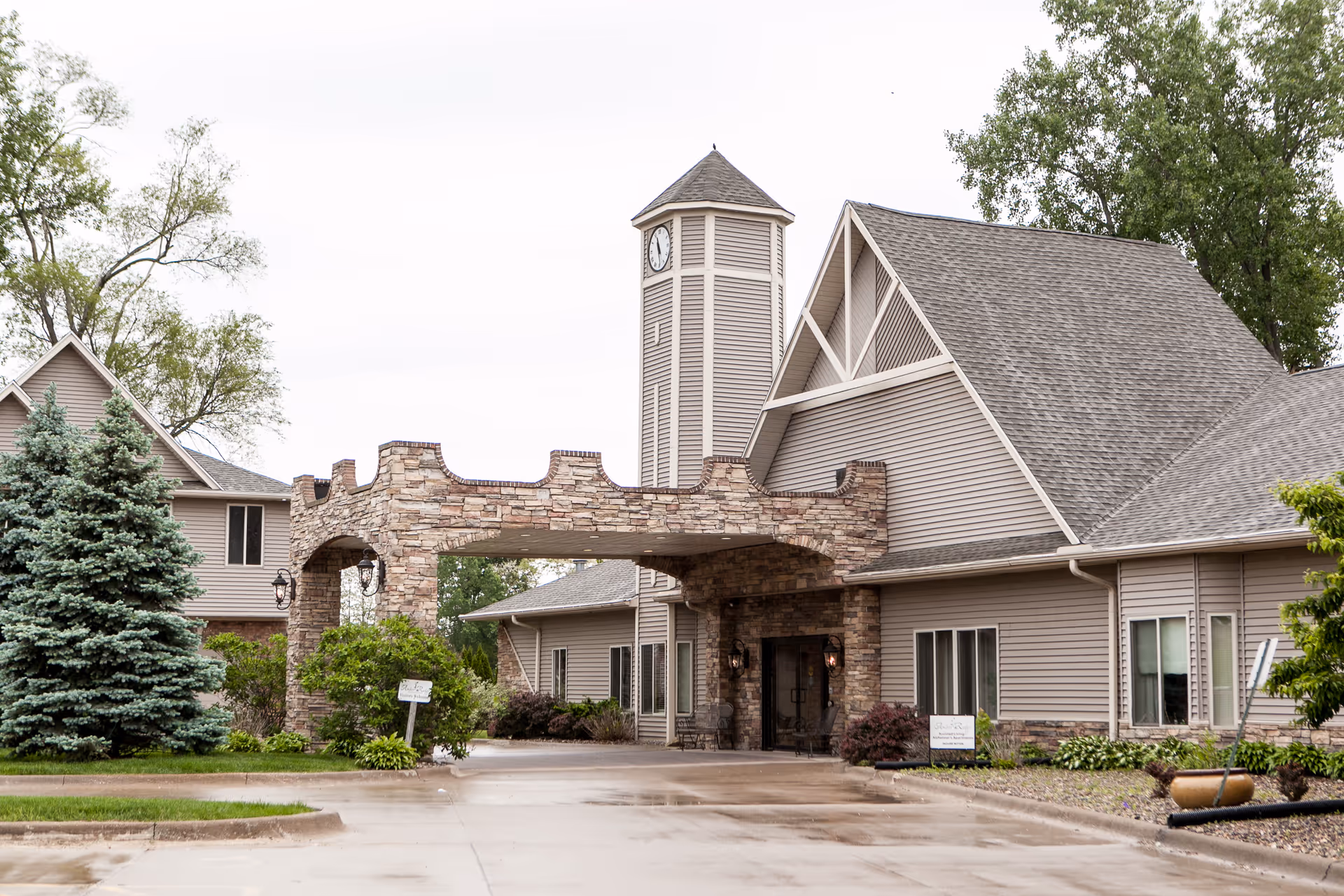 Exterior view of Charter Senior Living of Moline entrance with stone archway and clock tower.