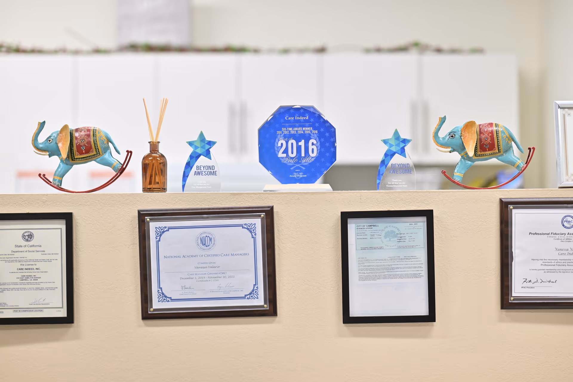Awards, certificates, and decorative elephant figurines displayed on a hallway ledge.