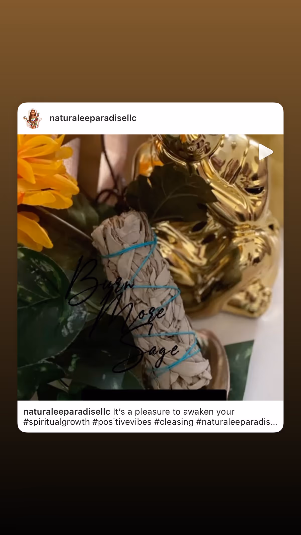 Close-up of wrapped sage bundle, yellow flowers, and a shiny gold statue on a table.