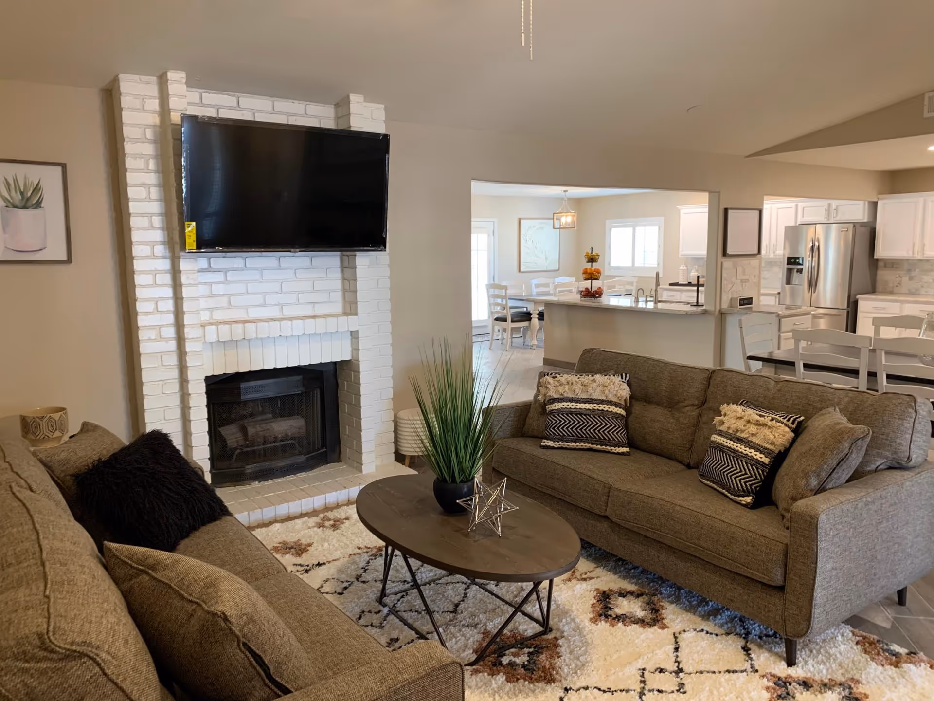 Cozy living room in a senior living facility with a fireplace, mounted TV, and open kitchen.