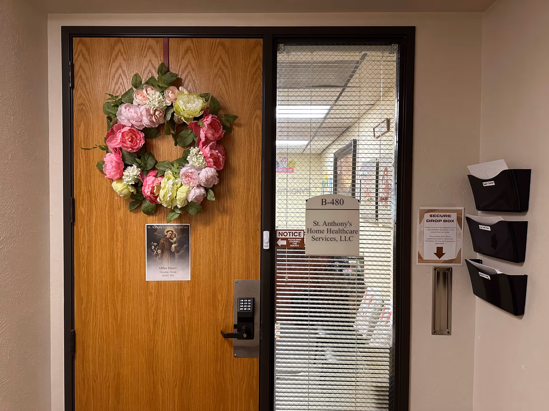 Wooden door with pink wreath beside glass entry door for St Anthony's Home Health Care.