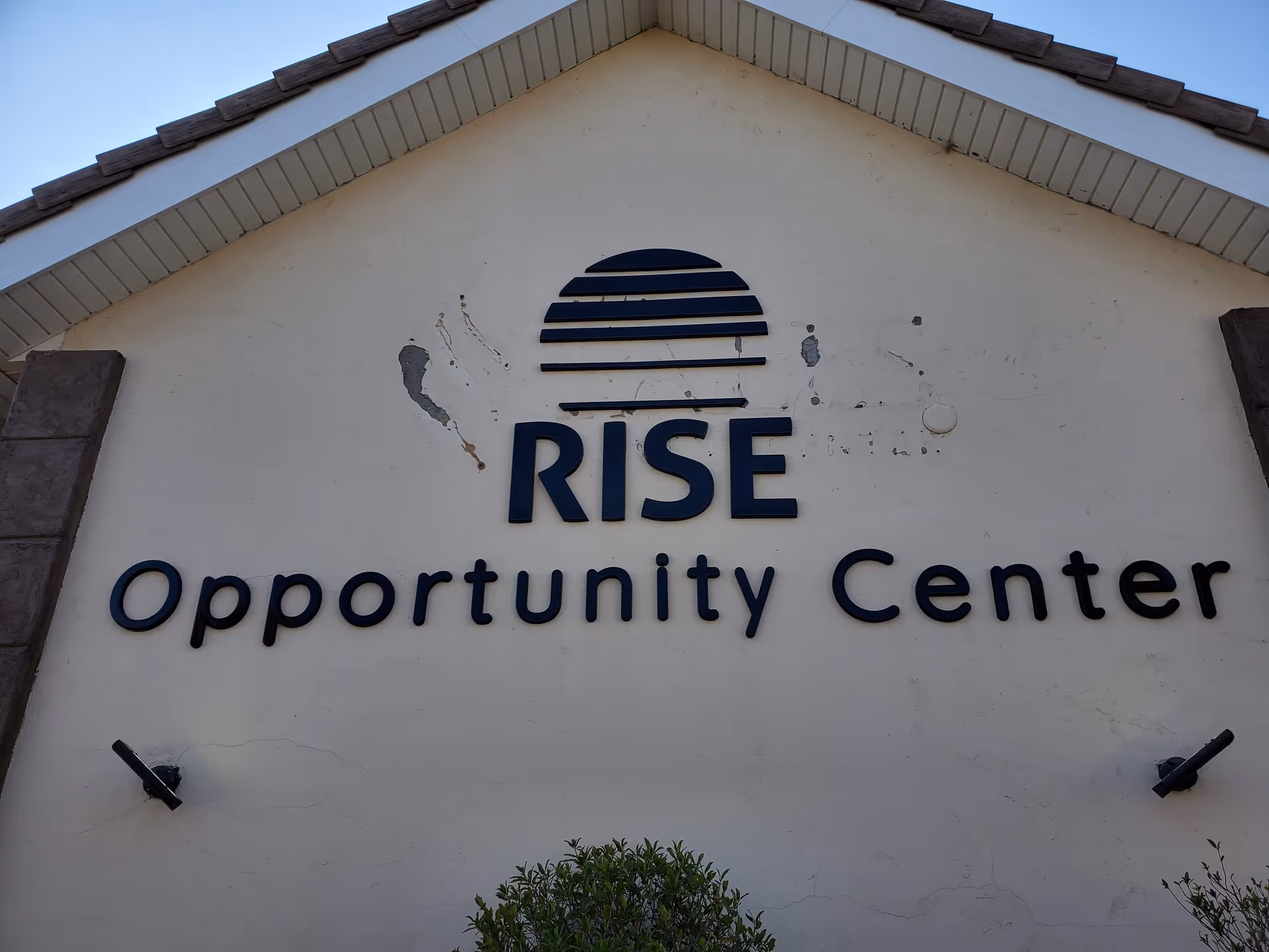 Facade of Rise Opportunity Center with a large blue sign on a pale wall.