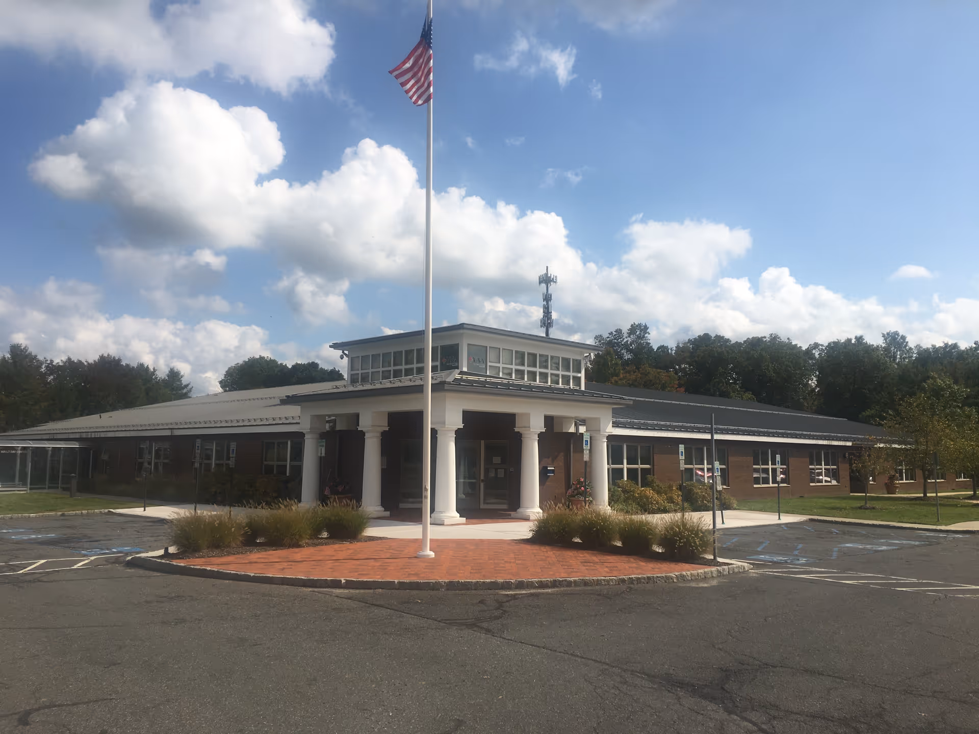Front view of Atlantic Private Care facility with entrance columns, flagpole, and parking.