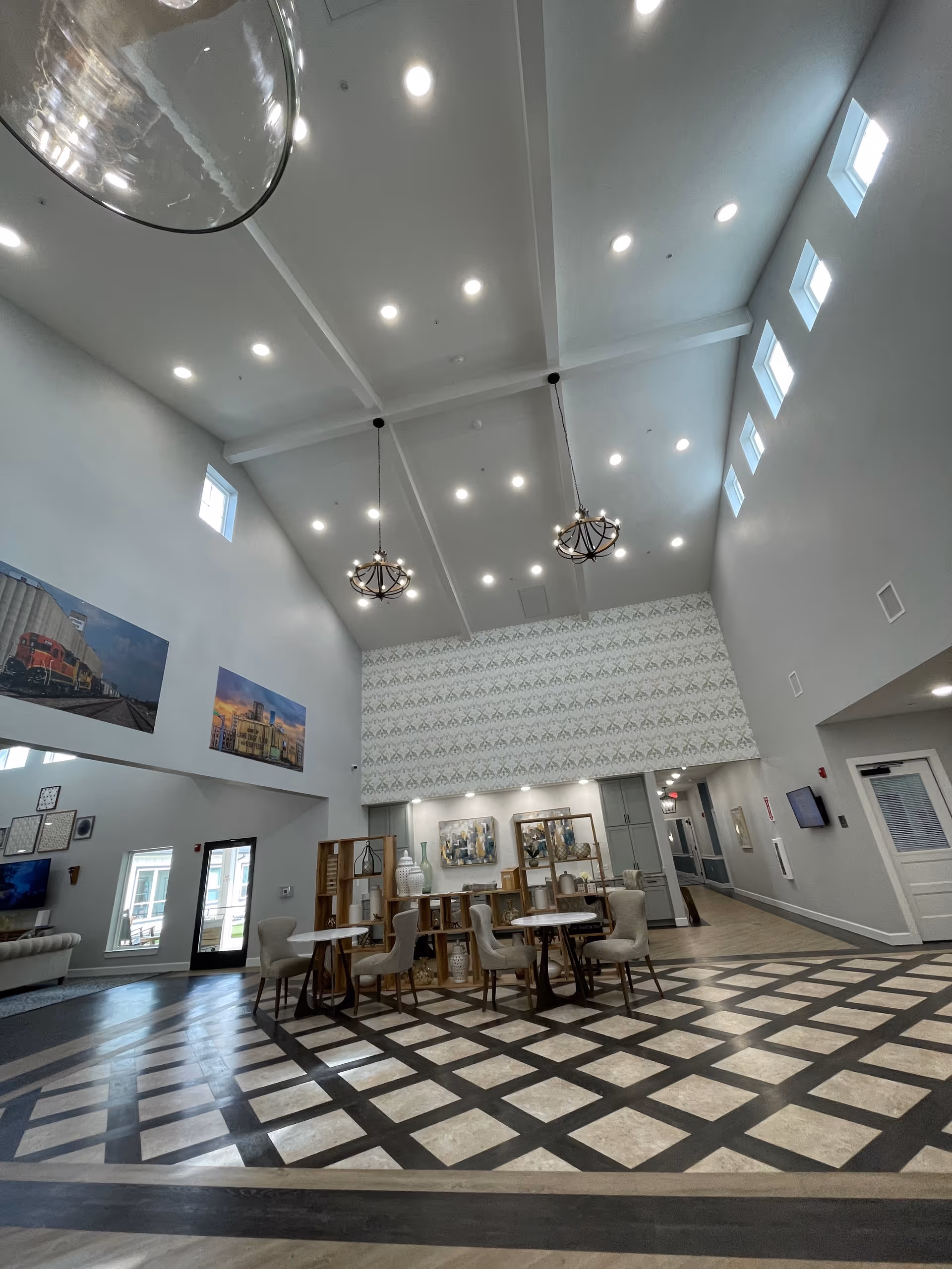 Spacious senior living lobby with high vaulted ceiling, chandeliers, and seating area.