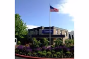 Exterior view of Colonial Park Care Center with flagpole and flowering shrubs.