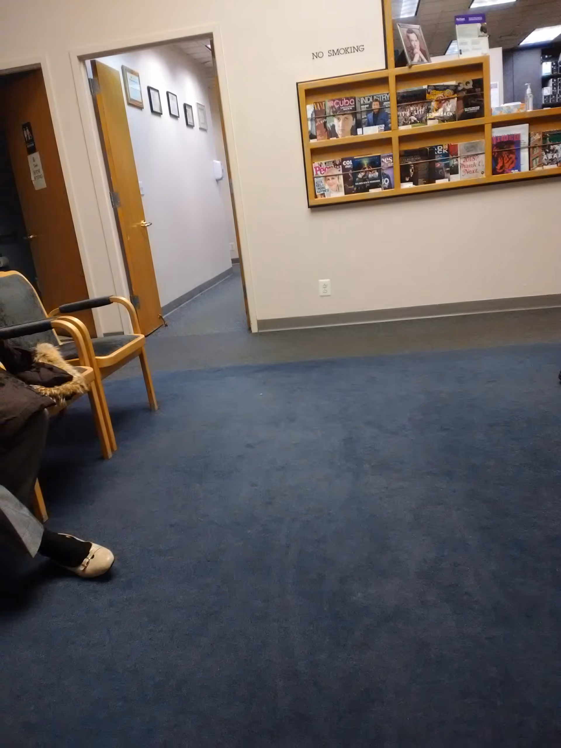 Interior corridor of an ambulatory care center with blue carpet, seating, and magazine racks.