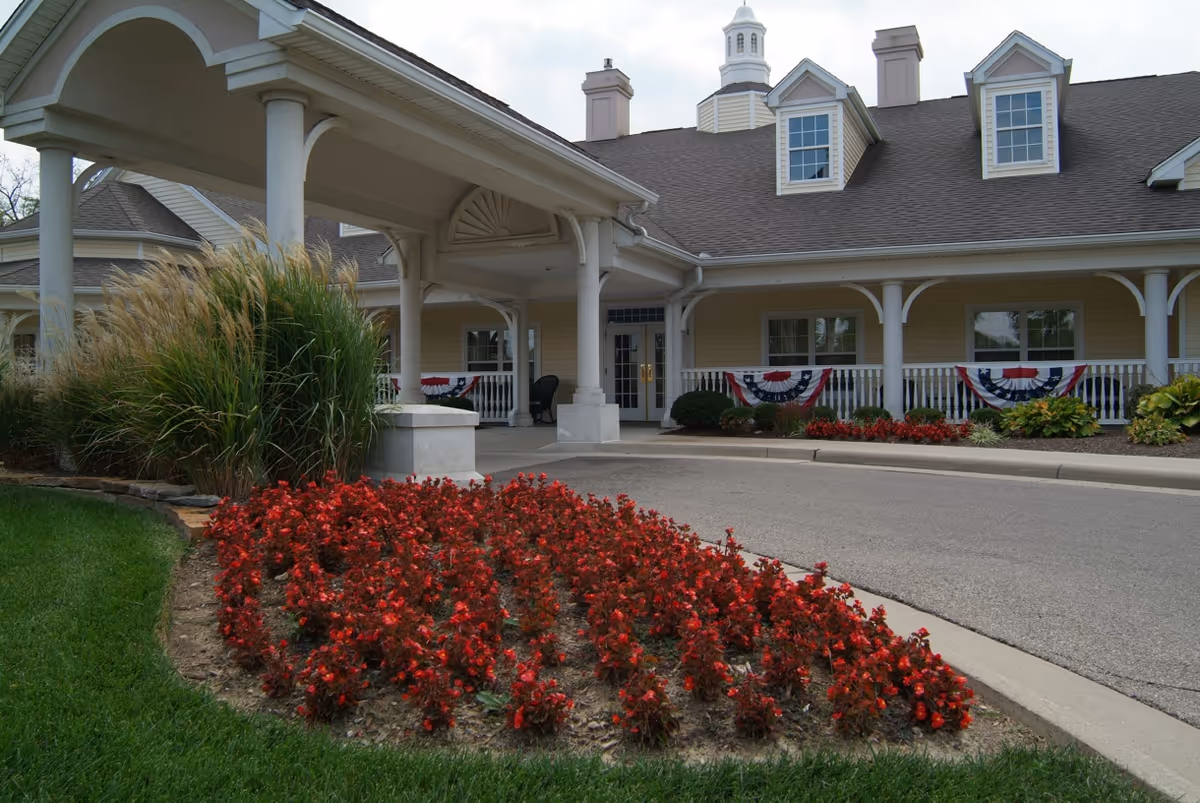 Front view of Bedrock at Home facility with covered entrance, bunting, and landscaped flower beds.
