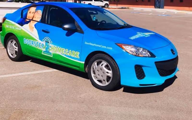 Blue and green DoorStep HomeCare branded car parked in an empty parking lot.
