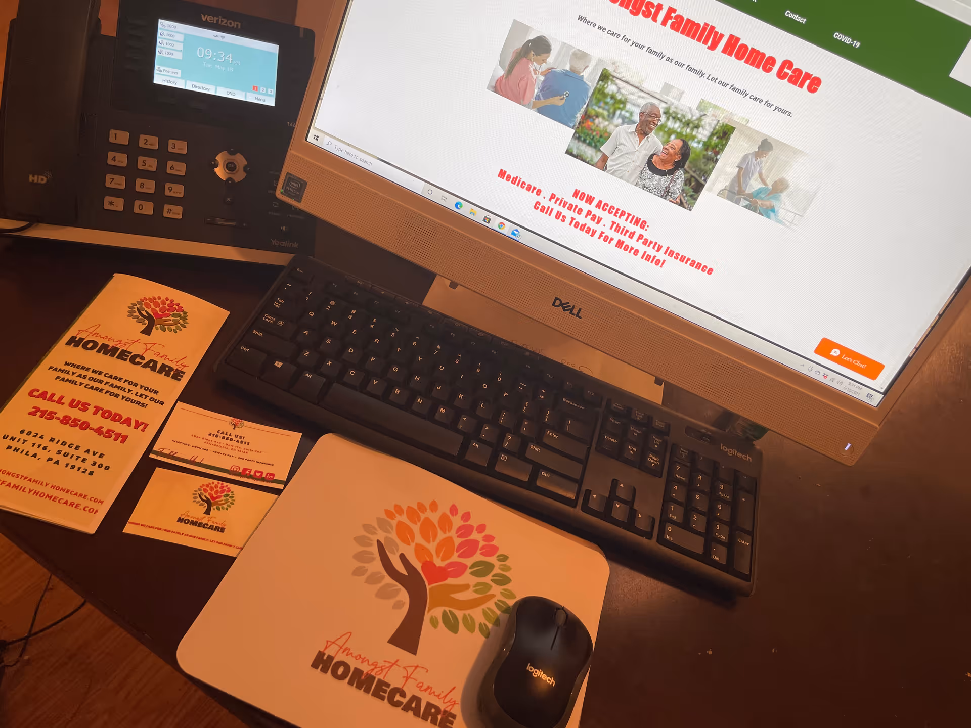 Desk setup with Dell monitor, keyboard, mouse, and business cards for Amongst Family Home Care.