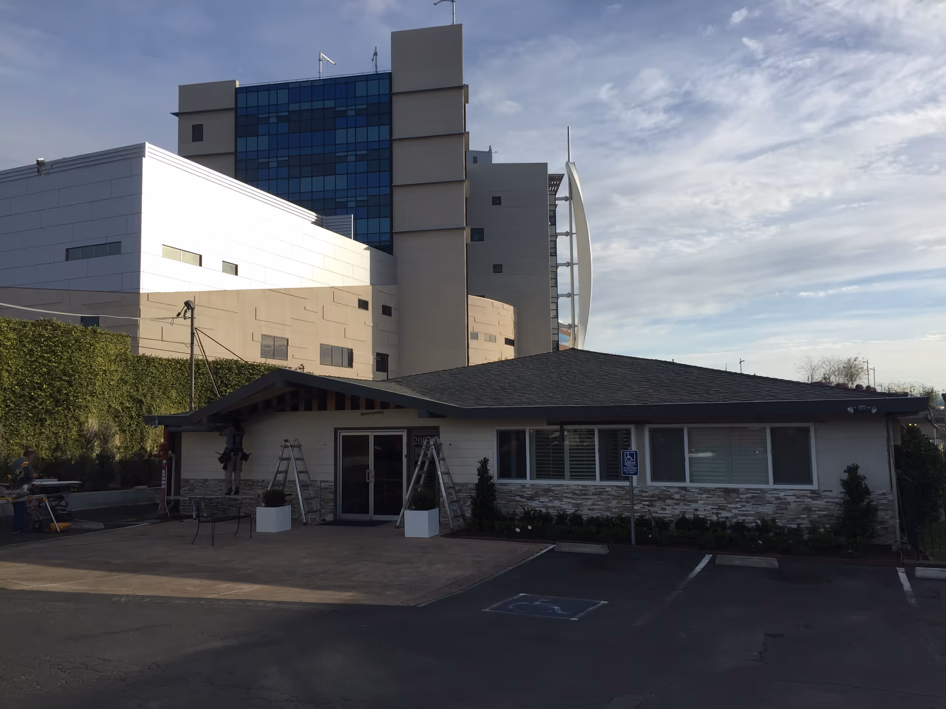 Front view of a single-story facility with a tall modern building behind.