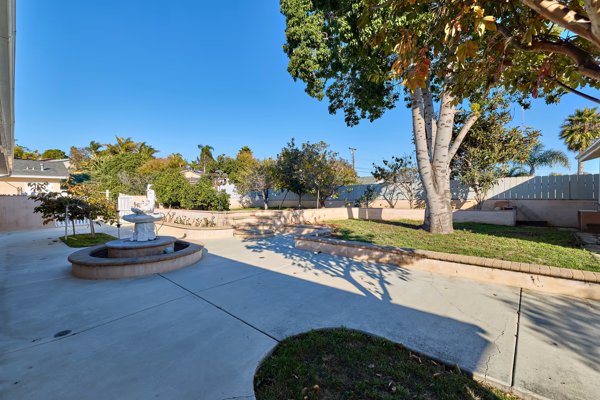 Sunny outdoor courtyard at Oceanside Elderly Care Home with fountain and trees.