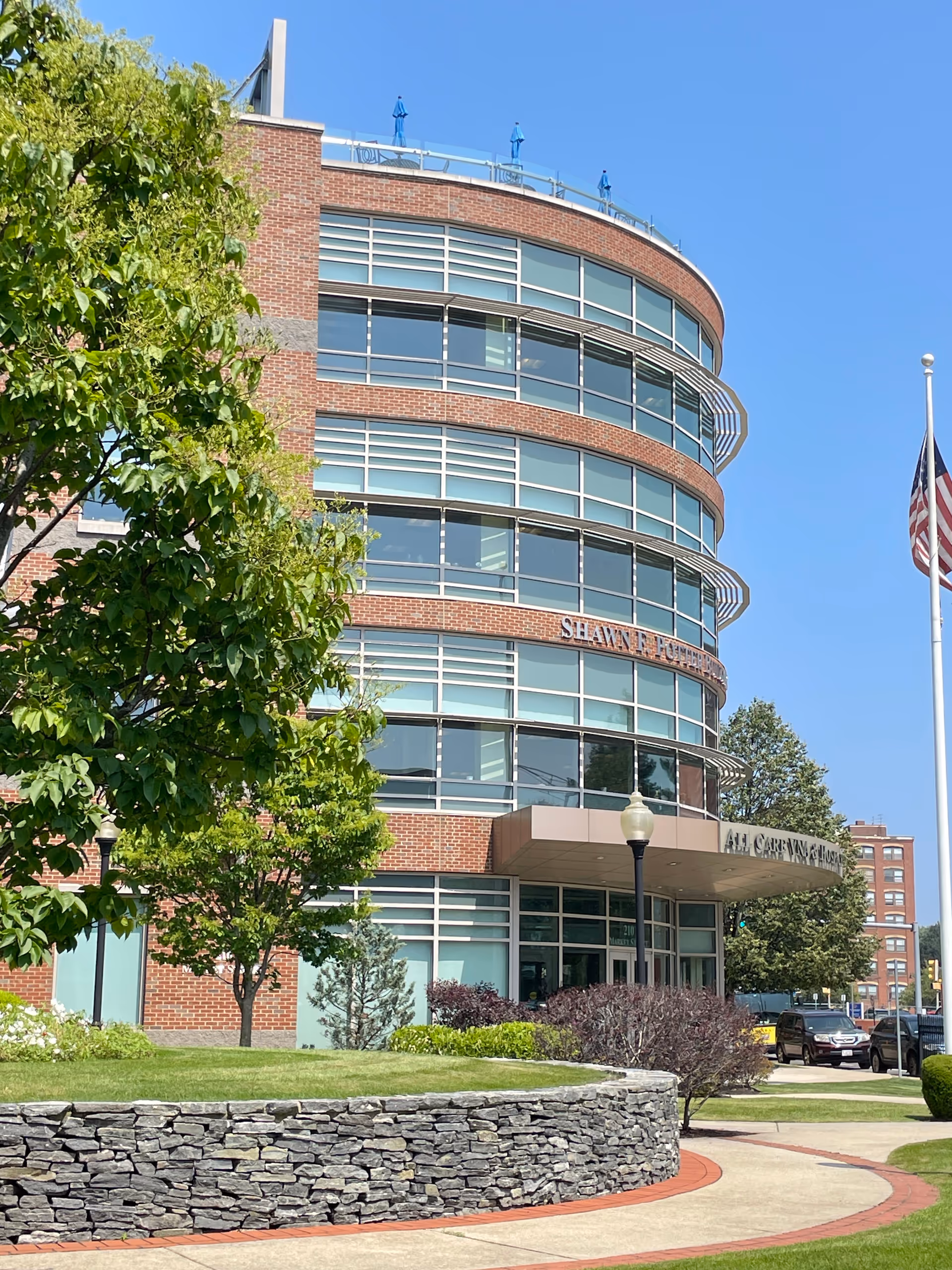 A curved brick-and-glass senior living building front with entrance and landscaping.