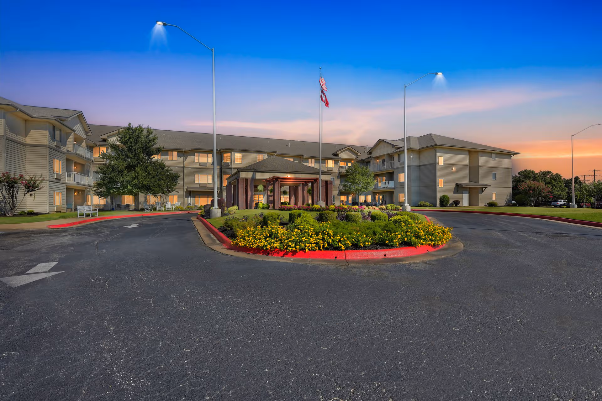 Exterior view of a senior living facility with a circular driveway and landscaped island.