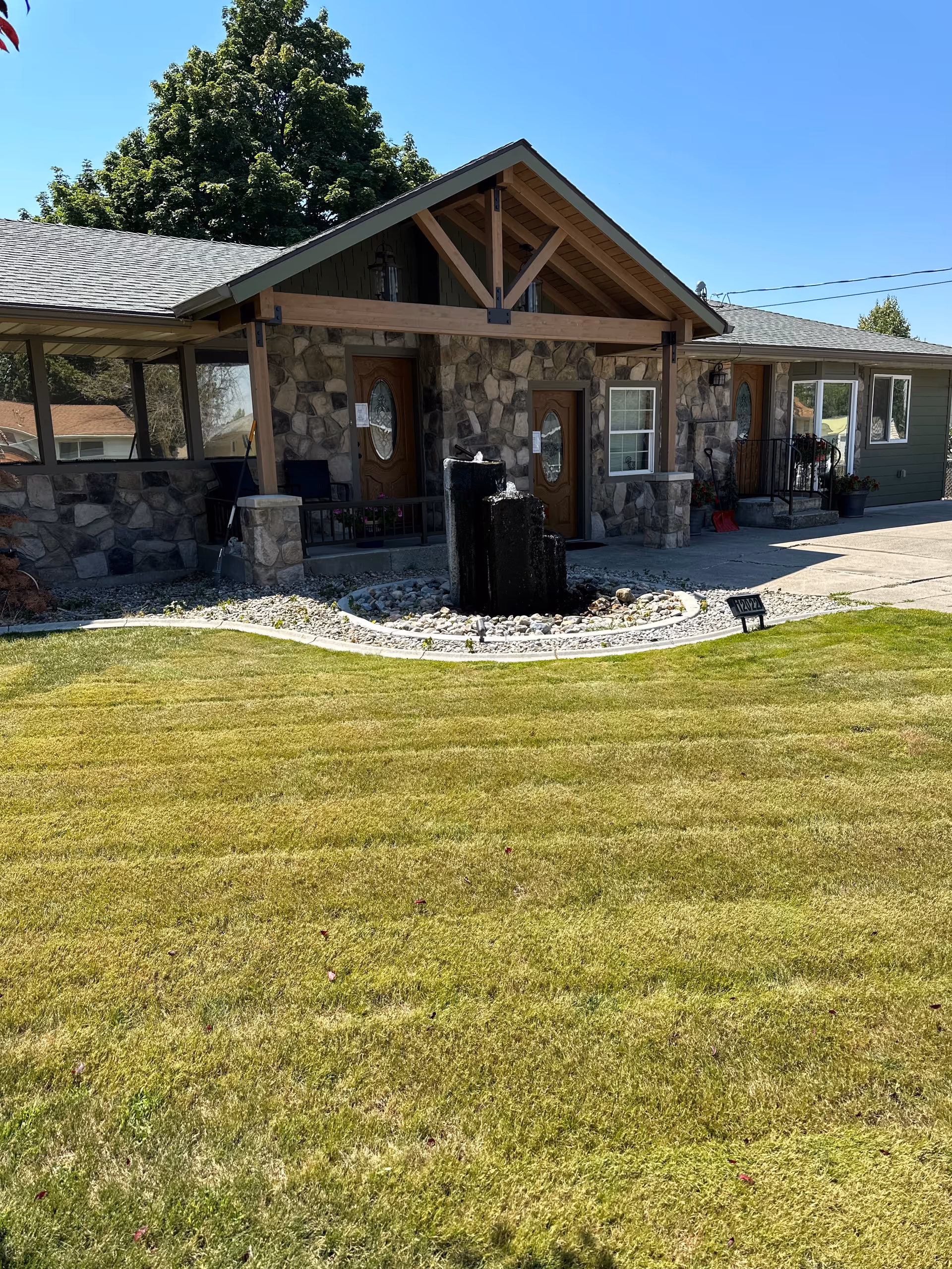 Front view of a stone Valley Pines retirement home with fountain and landscaped lawn.