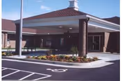 Exterior view of a brick senior living entrance with a covered drop-off and parking.