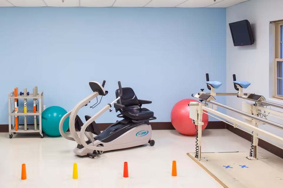 Interior of a senior living facility fitness room with exercise bike, balls, and cones.