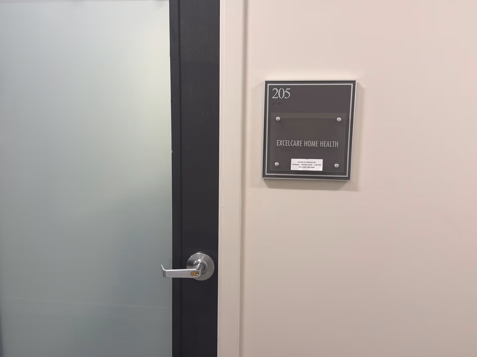 Interior hallway with a frosted glass door and a plaque reading 205 and Excelcare Home Health.