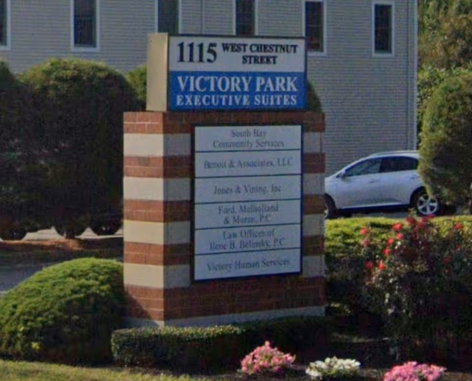 Front sign for Victory Park Executive Suites beside a brick building.