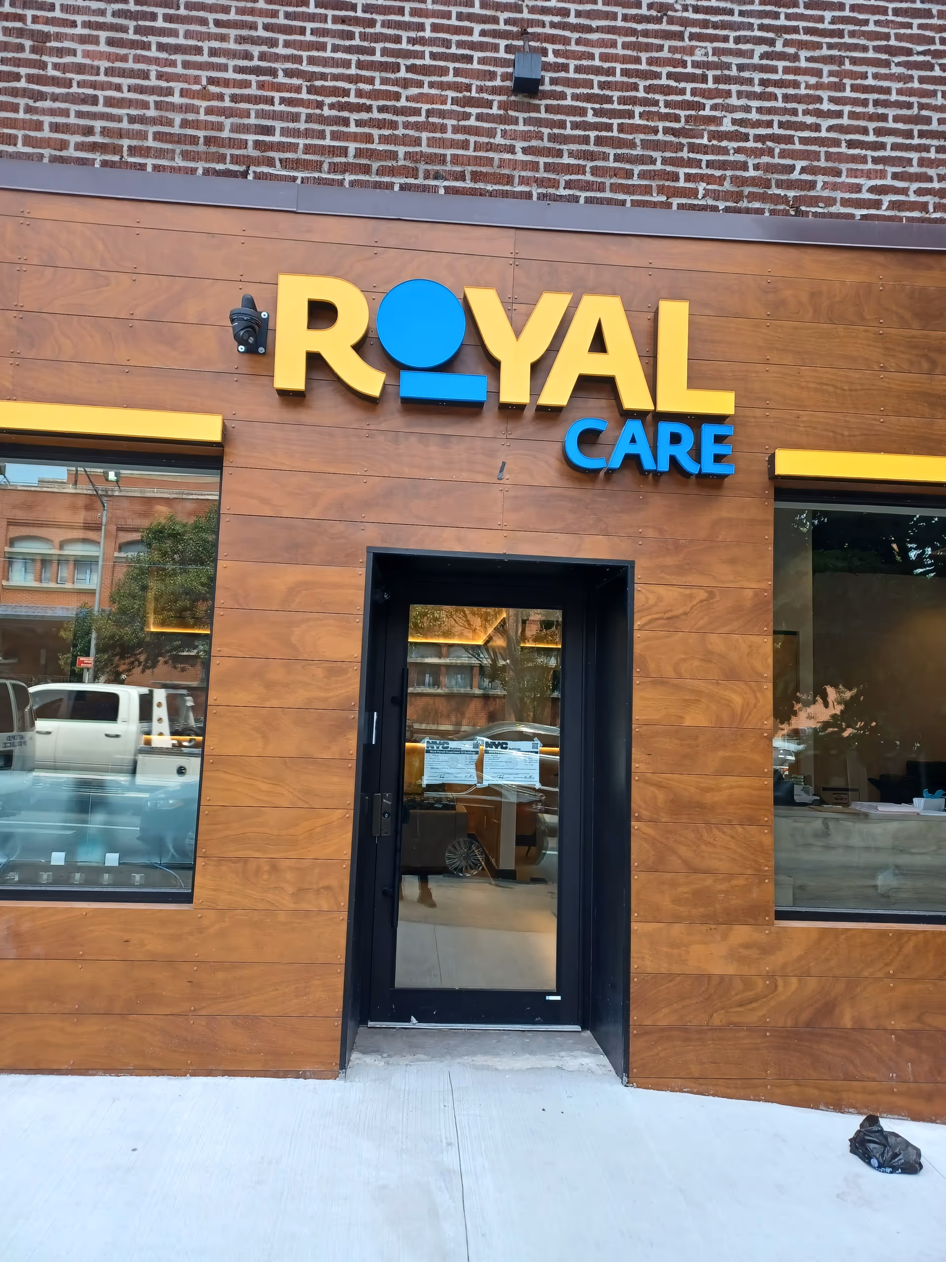Front exterior of Royal Care facility with wooden panels and glass entrance door.